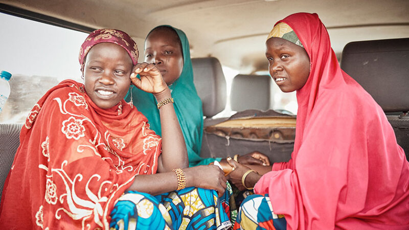Three women ride in an automobile.